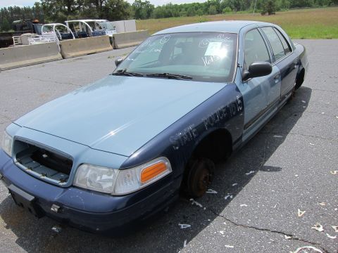1991 Ford LTD Crown Victoria - A two-tone police car, marked "STATE POLICE 1015", sits in a lot with its wheels removed.