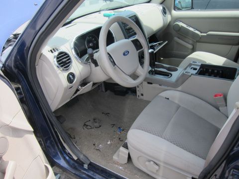 1991 Ford LTD Crown Victoria - The interior of a blue Ford Explorer, a tan dashboard and seats, is visible from the driver's side door.