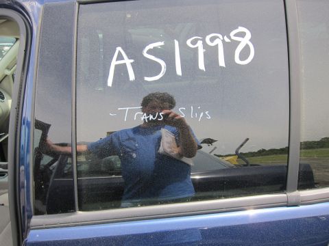 1991 Ford LTD Crown Victoria - Writing on car window shows 'AS1998' and '-Trans slips' with a person's reflection.