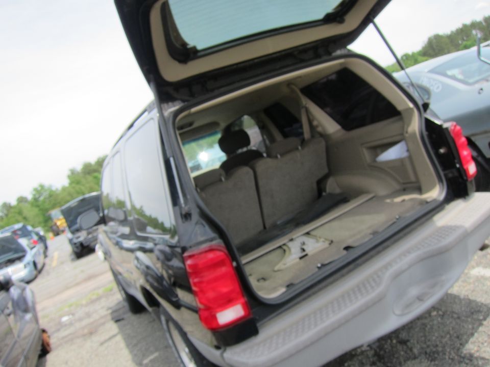 Black SUV with open tailgate, showing empty cargo area and folded seats. Other vehicles visible in background