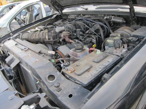 1991 Ford LTD Crown Victoria - Close-up view of a vehicle's engine bay, showing various mechanical parts and a battery.