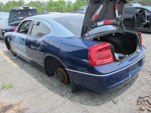 1991 Ford LTD Crown Victoria - This Dodge Charger is missing its wheels and has its trunk open, parked in a junkyard.