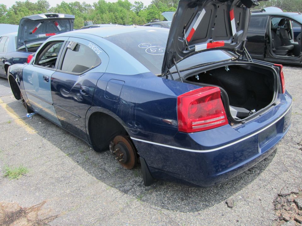 Blue Dodge Charger with missing wheels and open trunk. Another car is visible behind it