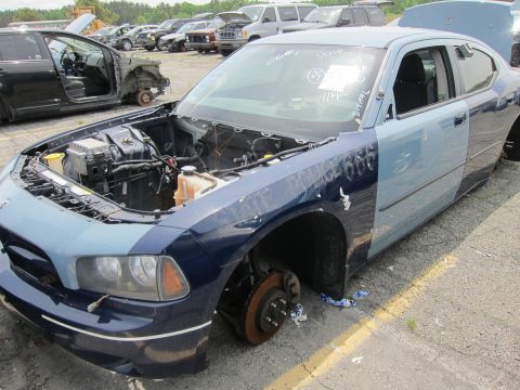 1991 Ford LTD Crown Victoria - A damaged police car sits in a junkyard, missing parts and showing "POLICE 666" on its side.