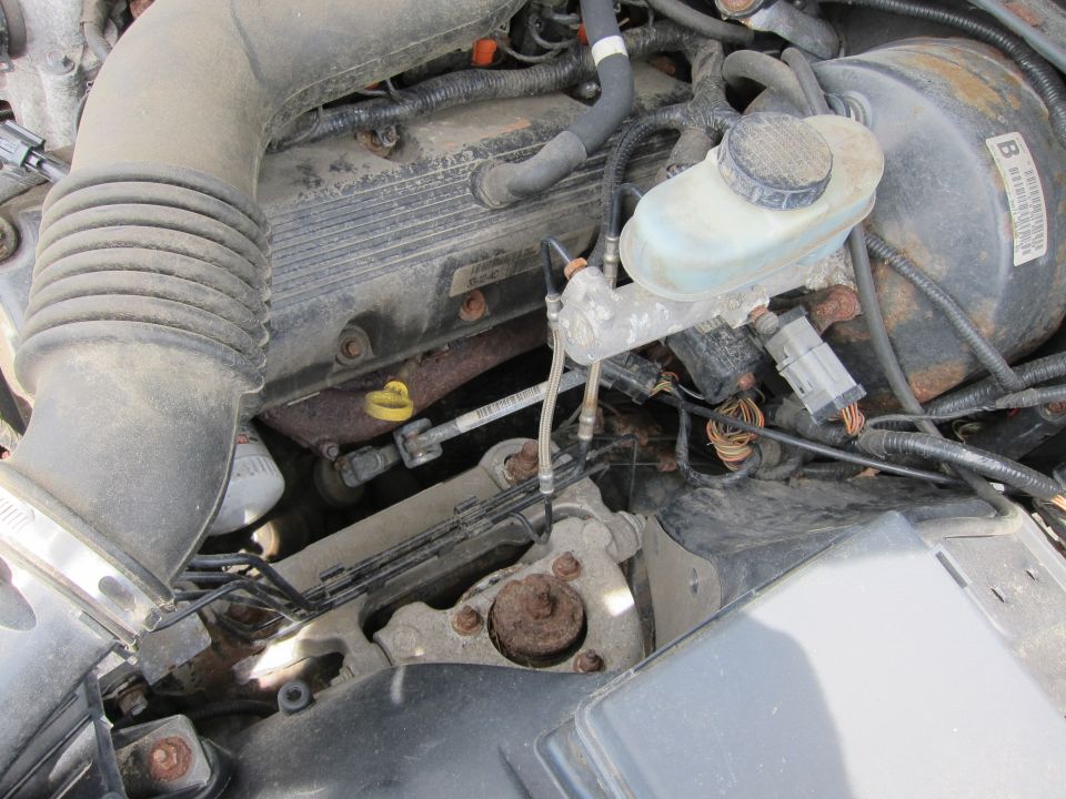 Close-up of engine bay showing air intake tube, valve cover, brake fluid reservoir, and brake booster