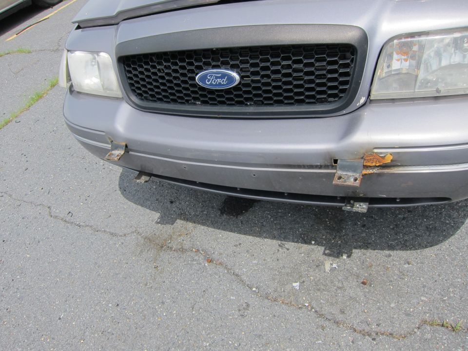 Front of a grey Ford Crown Victoria with a honeycomb grille and Ford badge
