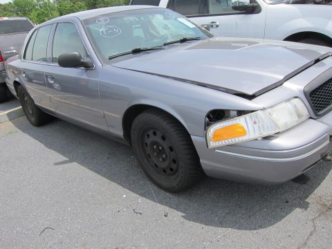 1991 Ford LTD Crown Victoria - A silver Ford Crown Victoria sedan is parked outdoors, showing damage to its front passenger side headlight assembly.