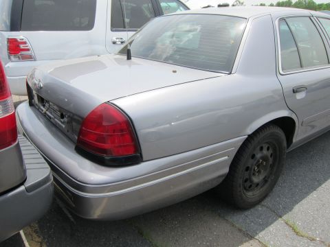 1991 Ford LTD Crown Victoria - Rear view of a silver sedan, parked next to other vehicles.