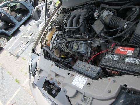 1991 Ford LTD Crown Victoria - Engine compartment details of a car, with a partial view of another vehicle in the background.