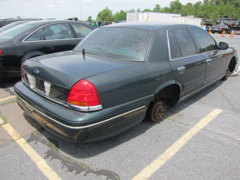 1991 Ford LTD Crown Victoria - A dark green sedan, likely from the early 2000s, sits without wheels in a parking lot.