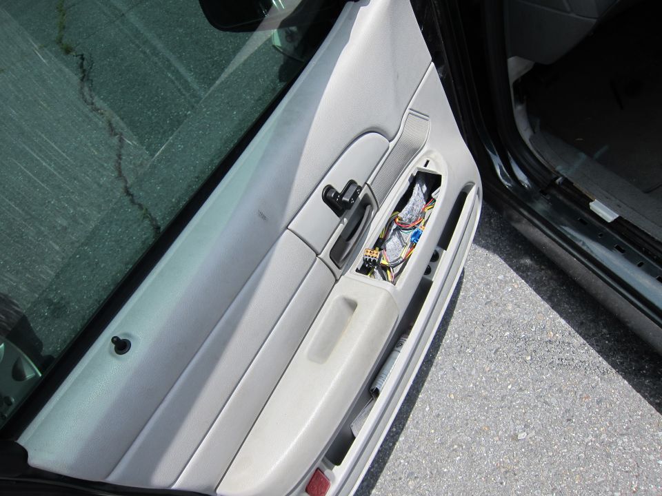 Car interior door panel with exposed wiring and components, light gray color, viewed from the side