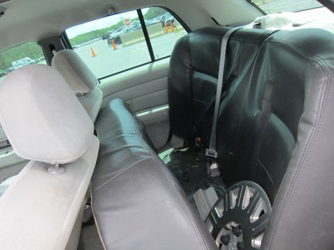 1991 Ford LTD Crown Victoria - The interior of a car shows the back seats, floor, and some items stored within.