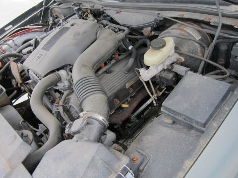 1991 Ford LTD Crown Victoria - Close-up view of a dusty engine bay, showing the V8 engine components and associated hardware.