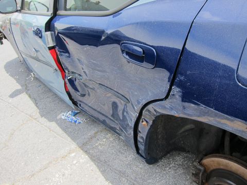 1991 Ford LTD Crown Victoria - The rear quarter panel and door of a blue sedan show significant collision damage.