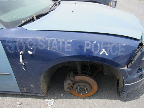 1991 Ford LTD Crown Victoria - Front fender of a blue police car with "609 STATE POLICE" text, missing its front wheel and showing damage.