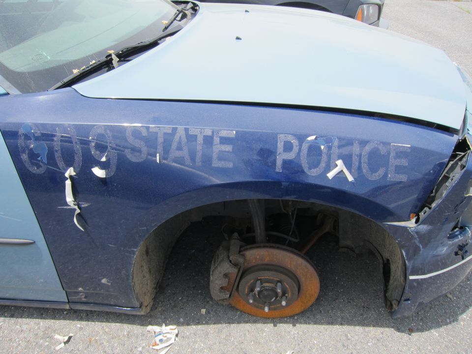 Blue police car fender with "609 STATE POLICE" text, missing wheel