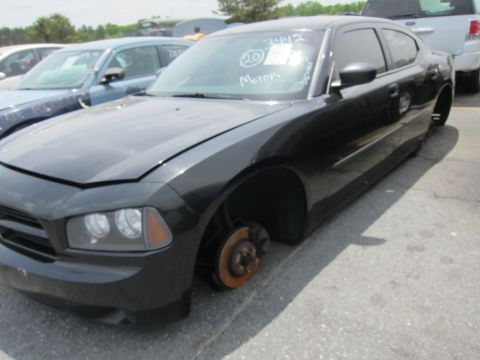 1991 Ford LTD Crown Victoria - A black Dodge Charger sits in a lot with its hood up and missing wheels, other vehicles visible in the background.