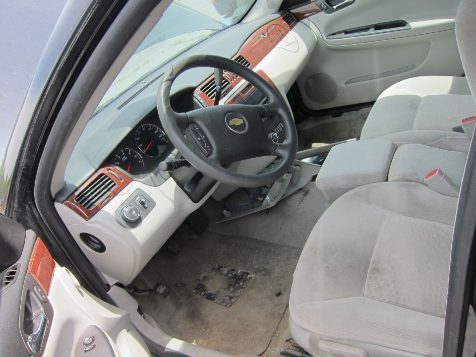 Car interior with light-colored cloth seats, wood trim, and a Chevrolet steering wheel