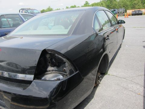 1991 Ford LTD Crown Victoria - Rear view of a black sedan with significant damage to the rear quarter panel and missing a rear wheel.