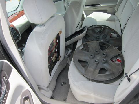 1991 Ford LTD Crown Victoria - Interior view of a car with hubcaps stored on the back seat and exposed wiring on the side of the front seat.
