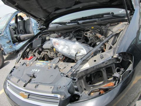 1991 Ford LTD Crown Victoria - Junked black car with hood open, showing engine and missing headlight. A damaged blue car is in the background.