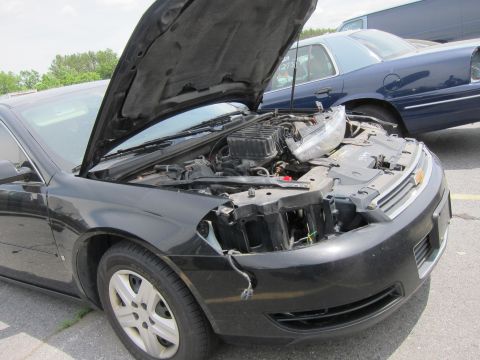 1991 Ford LTD Crown Victoria - Front view of a black car with its hood open, revealing the engine compartment and a damaged headlight.