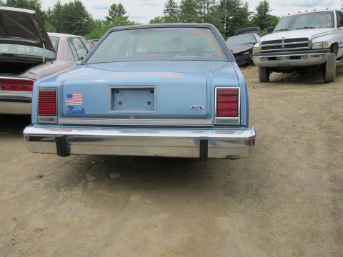 2001 Ford Crown Victoria - Light blue sedan's rear end with chrome bumper and American flag sticker visible.