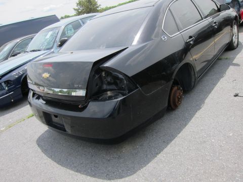 1991 Ford LTD Crown Victoria - A black sedan sits in a lot with its rear passenger wheel removed and visible damage to the body.