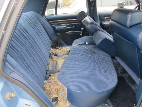 2001 Ford Crown Victoria - The interior of a car shows worn blue seats and a floor littered with debris.