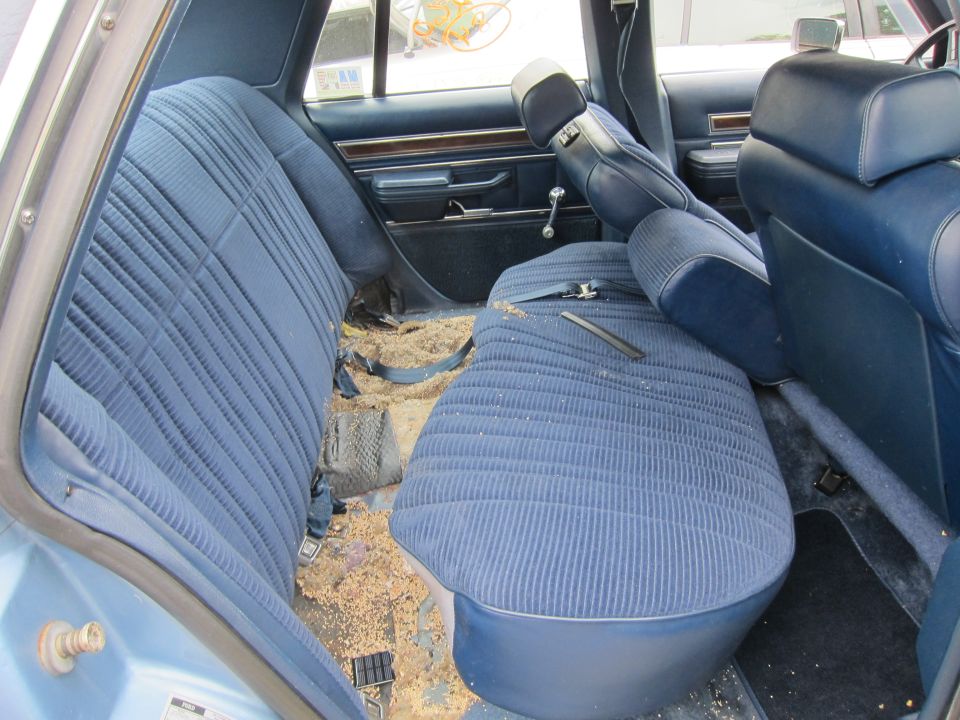 Blue fabric seats and floor are covered in debris inside a car