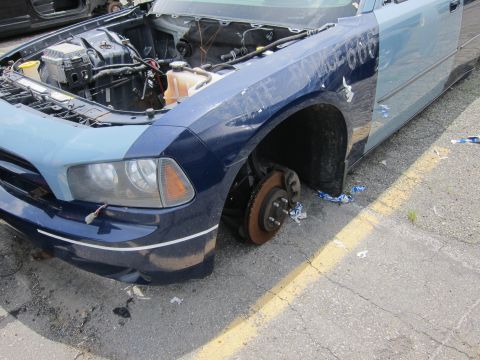 1991 Ford LTD Crown Victoria - This damaged police car is missing a wheel and has its hood open, revealing the engine compartment.