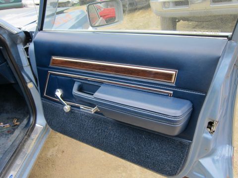 2001 Ford Crown Victoria - Close-up of a car's interior door panel, showing blue upholstery and wood grain accents.