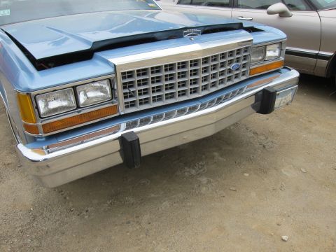 2001 Ford Crown Victoria - Front view of a blue sedan a chrome grille and bumper, with another vehicle visible behind it.