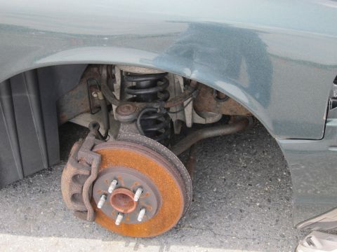 1991 Ford LTD Crown Victoria - Front suspension and brake assembly with significant rust on the rotor.
