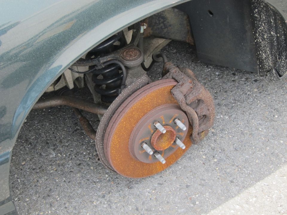 Close-up of a rusty brake rotor and caliper on a vehicle