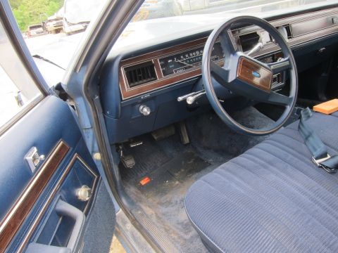 2001 Ford Crown Victoria - The interior of a vintage sedan reveals a blue fabric seat, dashboard, and steering wheel.