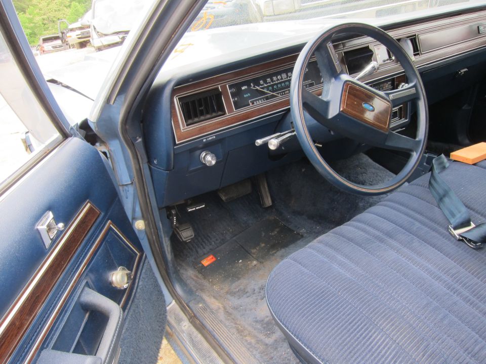 Blue fabric seats and dashboard of an old car, showing the steering wheel, instrument cluster, and door panel