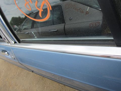 2001 Ford Crown Victoria - A blue car door is shown with a reflection of another vehicle in its window, which has markings on it.