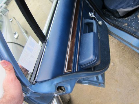 2001 Ford Crown Victoria - Close-up of a blue interior door panel wood trim, a chrome handle, and a sticker on the window.