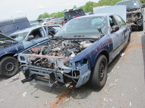 1991 Ford LTD Crown Victoria - This 1991 Ford Crown Victoria LTD shows significant front-end damage and is in a junkyard setting.