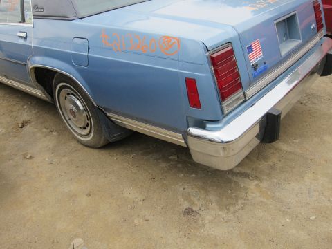2001 Ford Crown Victoria - Rear view of a blue sedan with graffiti and an American flag sticker on the trunk lid.