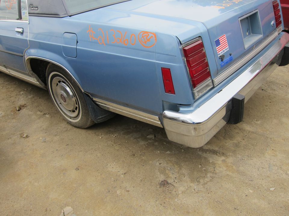 Blue sedan rear quarter panel with orange graffiti and an American flag sticker