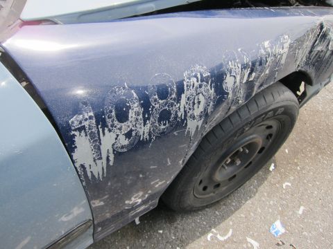 1991 Ford LTD Crown Victoria - The fender of a blue car has large, peeling white numbers that appear to read 1986.