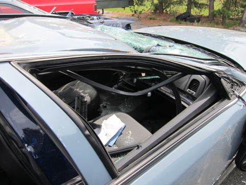1991 Ford LTD Crown Victoria - Interior of a heavily damaged light blue sedan, showing a broken windshield and crumpled roof structure.