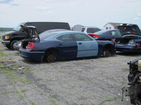 1991 Ford LTD Crown Victoria - Junkyard scene with a damaged Dodge Charger missing wheels and a black van.