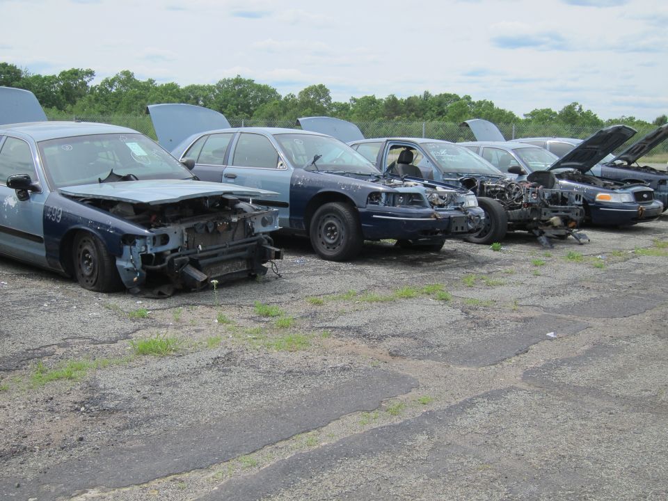 Line of damaged blue and light blue police cars with hoods up