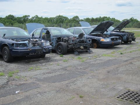 1991 Ford LTD Crown Victoria - Multiple Ford Crown Victorias are lined up in a junkyard, showing signs of disrepair.