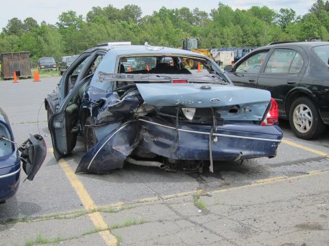 1991 Ford LTD Crown Victoria - This severely damaged sedan has its rear end completely crushed, with the driver's side door ajar.
