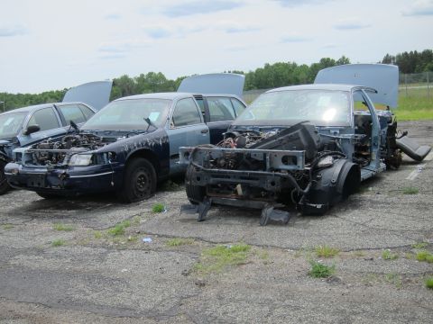 1991 Ford LTD Crown Victoria - Junkyard scene with multiple damaged sedans, one stripped of its front components.