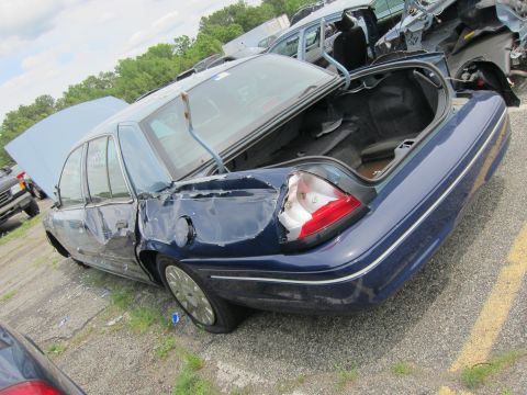 1991 Ford LTD Crown Victoria - This sedan has significant rear-end damage and is in a junkyard with other vehicles.